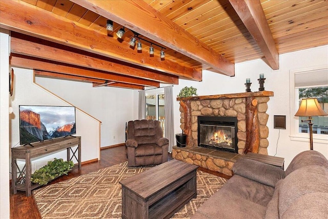 living room featuring dark hardwood / wood-style flooring, track lighting, beamed ceiling, and a fireplace