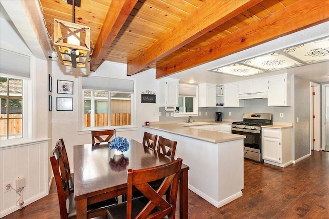 kitchen with white cabinetry, kitchen peninsula, gas stove, beam ceiling, and sink