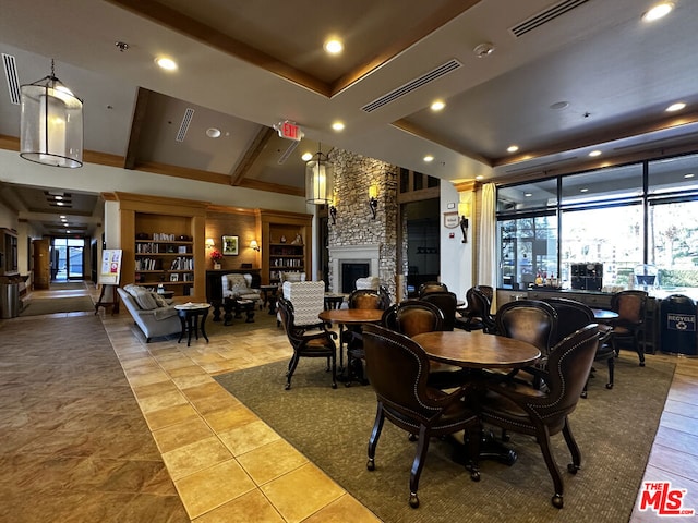 tiled dining room with a large fireplace and a tray ceiling