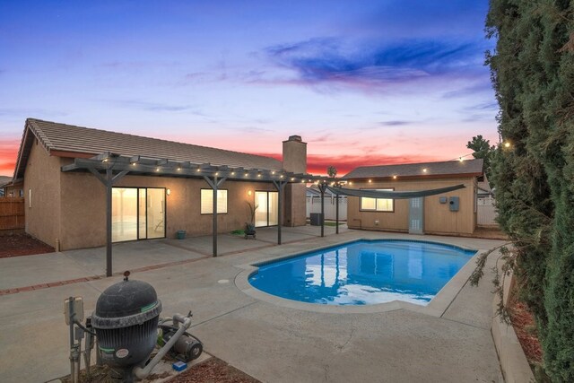 pool at dusk with a pergola and a patio