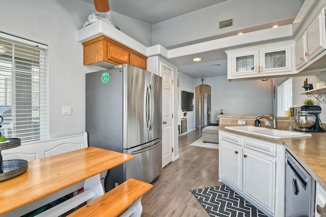 kitchen with sink, light hardwood / wood-style flooring, stainless steel appliances, and white cabinets