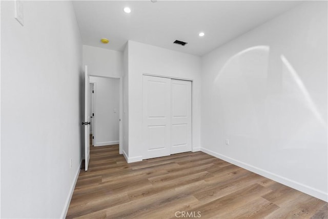 unfurnished bedroom featuring a closet and hardwood / wood-style floors