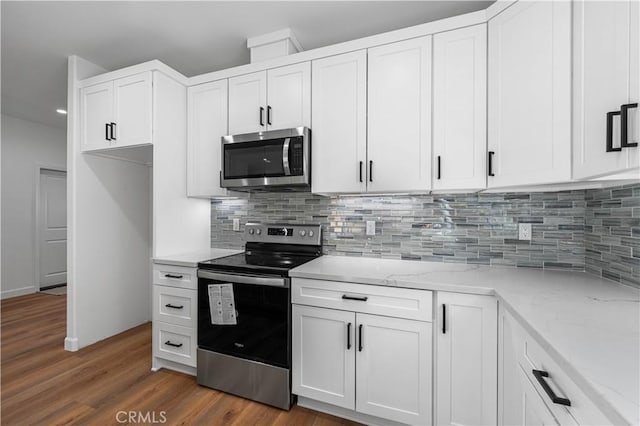 kitchen featuring light stone countertops, white cabinets, appliances with stainless steel finishes, dark hardwood / wood-style flooring, and tasteful backsplash