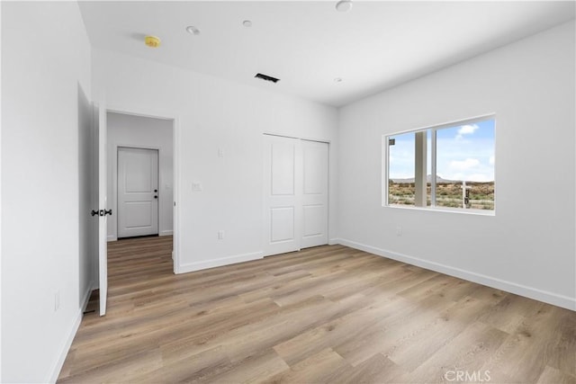 unfurnished bedroom featuring a closet and light hardwood / wood-style flooring