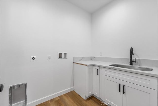 laundry area featuring light hardwood / wood-style floors, electric dryer hookup, hookup for a washing machine, cabinets, and sink