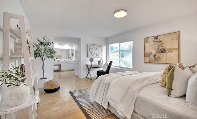 bedroom featuring light wood-type flooring and connected bathroom