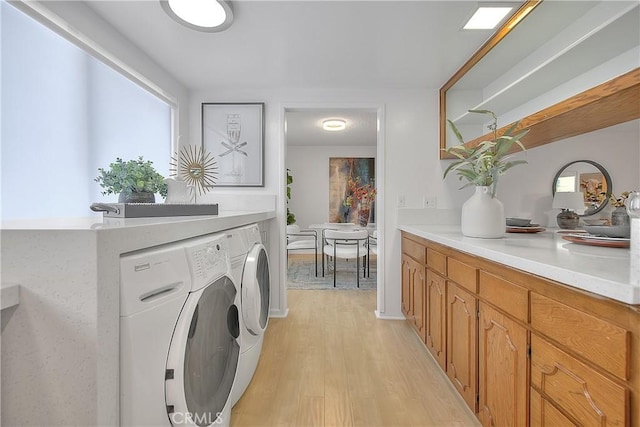 washroom with light wood-type flooring, cabinets, and washer and clothes dryer