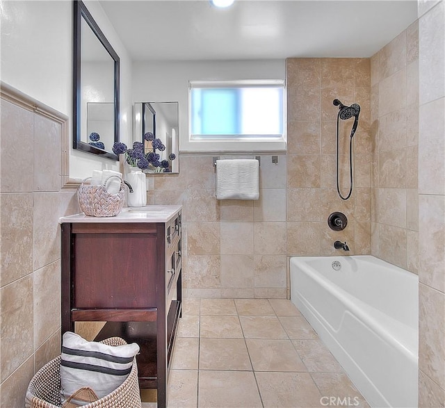 bathroom with tile patterned flooring, tile walls, vanity, and tiled shower / bath combo