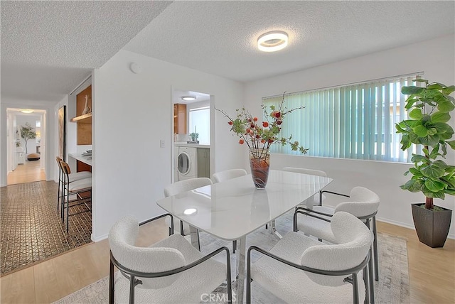 dining space with washer / dryer, a textured ceiling, and light hardwood / wood-style floors