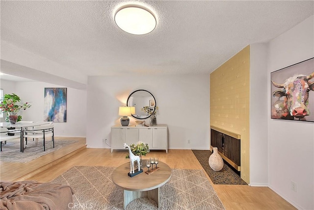 living room with light wood-type flooring, a fireplace, and a textured ceiling