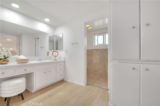 bathroom with hardwood / wood-style flooring, a textured ceiling, and vanity