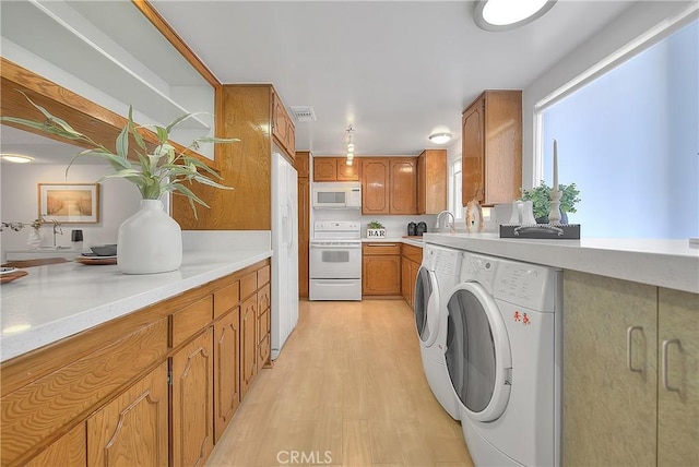 clothes washing area featuring washer and dryer, light hardwood / wood-style flooring, and sink