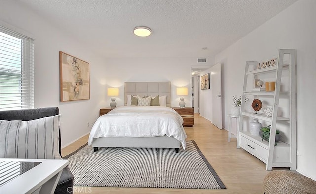 bedroom with a textured ceiling and light hardwood / wood-style flooring