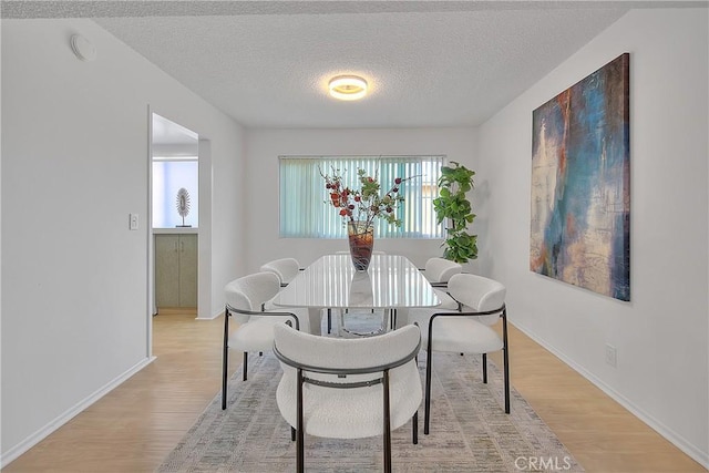 dining room featuring a textured ceiling and light hardwood / wood-style floors