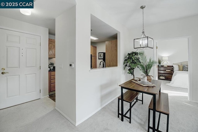 corridor featuring light colored carpet, an inviting chandelier, and sink