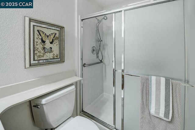 bathroom featuring toilet and a shower with shower door