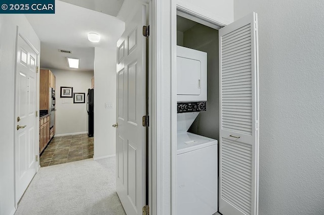 clothes washing area with stacked washer / dryer and light carpet