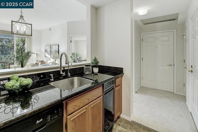 kitchen with dishwasher, light carpet, dark stone counters, sink, and a notable chandelier