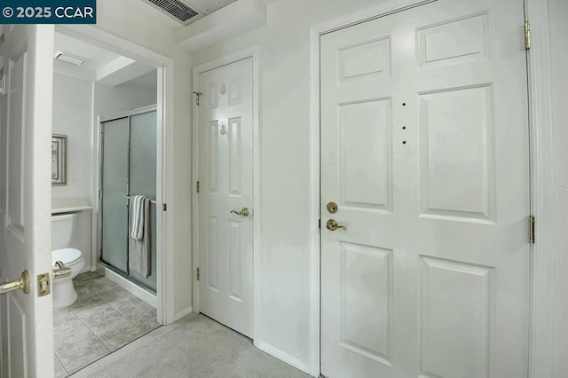 bathroom featuring toilet, tile patterned floors, and a shower with shower door