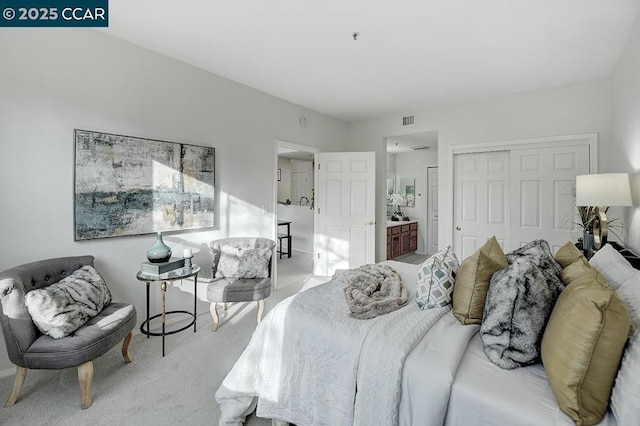 bedroom featuring ensuite bath, light colored carpet, and a closet