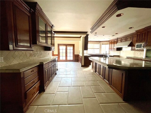 kitchen featuring decorative backsplash, dark brown cabinetry, crown molding, and french doors