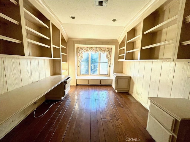 unfurnished office featuring built in shelves, dark hardwood / wood-style flooring, crown molding, and built in desk