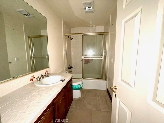 full bathroom featuring enclosed tub / shower combo, toilet, vanity, and tile patterned flooring