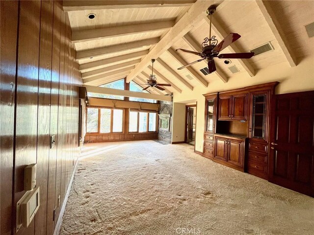 unfurnished living room featuring beam ceiling, ceiling fan, light carpet, and wooden walls