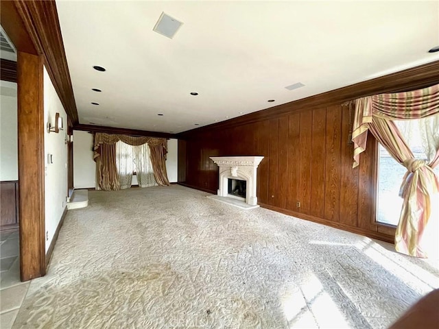 unfurnished living room featuring crown molding and wooden walls