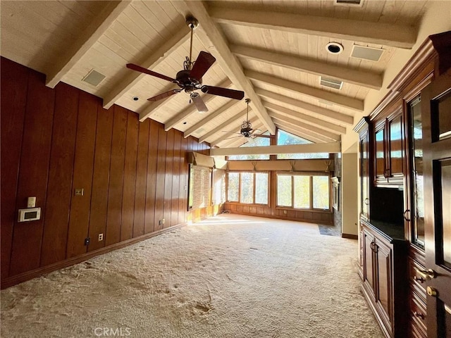 unfurnished living room with ceiling fan, lofted ceiling with beams, wood walls, and carpet flooring