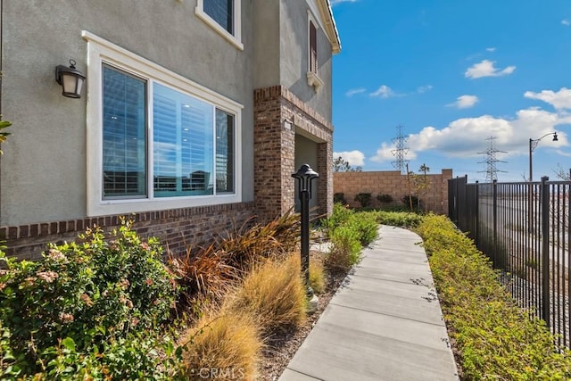 view of side of home featuring brick siding, fence private yard, and stucco siding