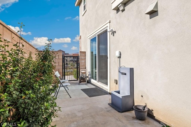 view of patio featuring a balcony and fence