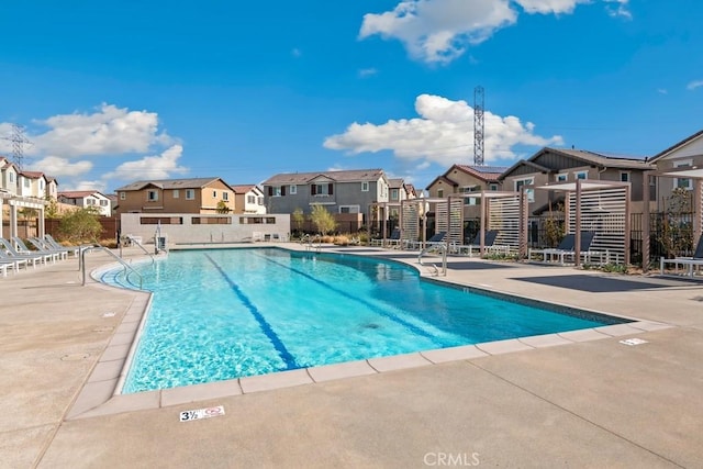 community pool with a residential view, a patio area, and fence