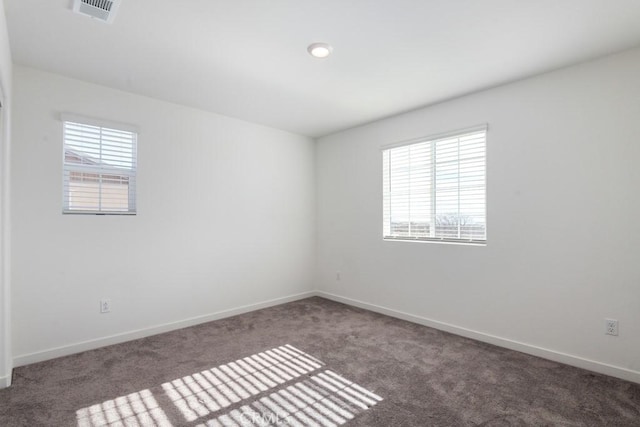 carpeted spare room with visible vents and baseboards