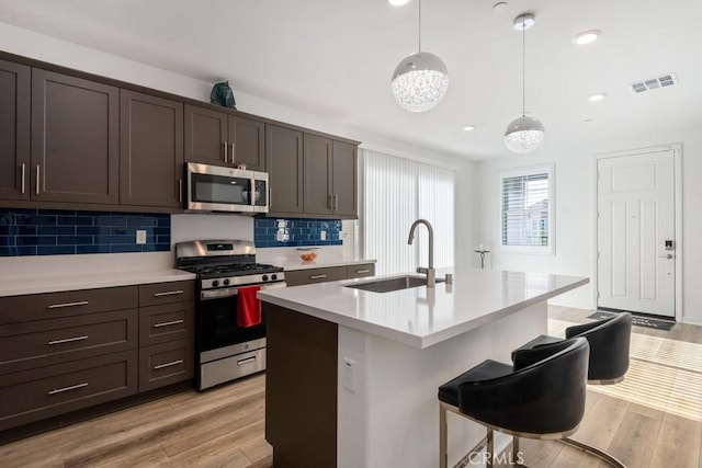 kitchen featuring stainless steel appliances, light wood-style flooring, a sink, and visible vents