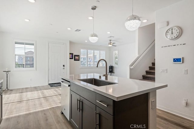 kitchen featuring stainless steel dishwasher, light wood-style flooring, light countertops, and a sink