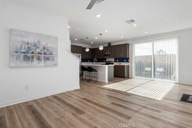 kitchen featuring dark brown cabinetry, visible vents, light wood-style floors, light countertops, and appliances with stainless steel finishes