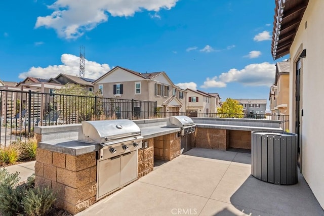 view of patio with exterior kitchen, area for grilling, a fenced backyard, and a residential view