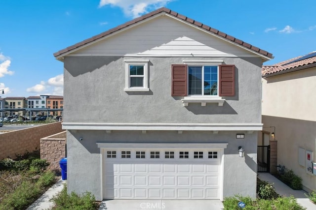 exterior space with a garage, concrete driveway, and stucco siding