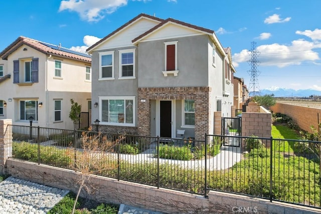 view of front of home featuring brick siding, a fenced front yard, a tile roof, and stucco siding