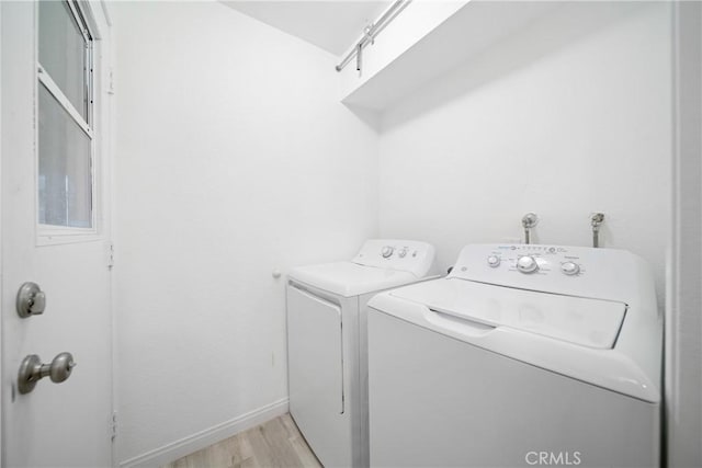 washroom featuring washing machine and clothes dryer and light hardwood / wood-style flooring