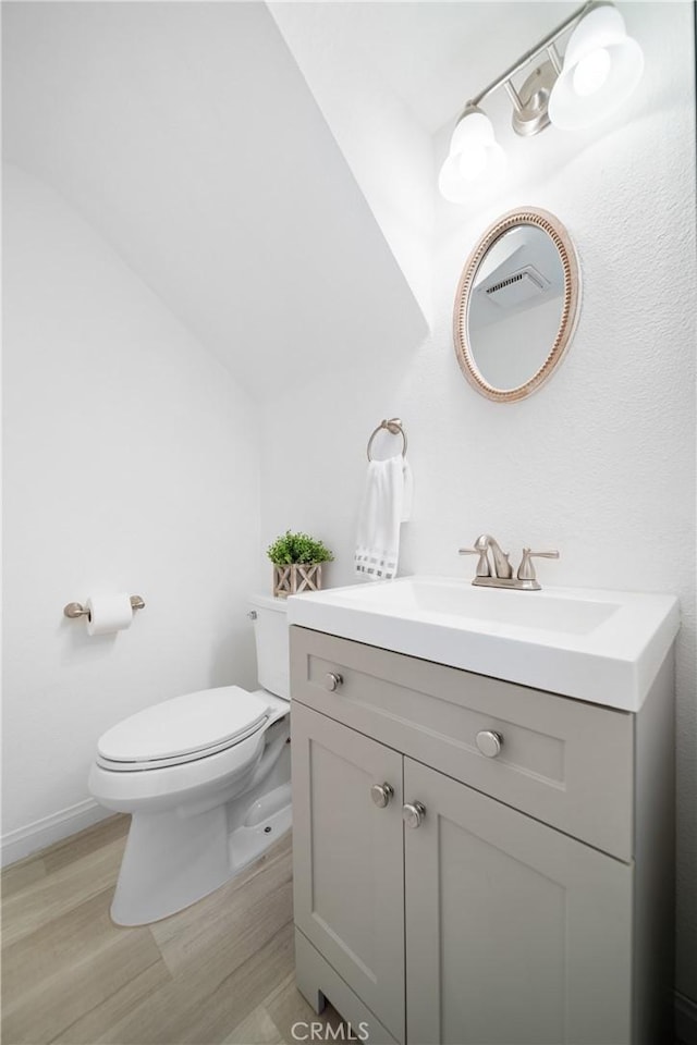 bathroom featuring wood-type flooring, toilet, and vanity