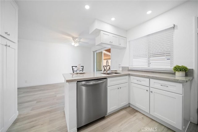 kitchen featuring dishwasher, kitchen peninsula, sink, white cabinetry, and light wood-type flooring