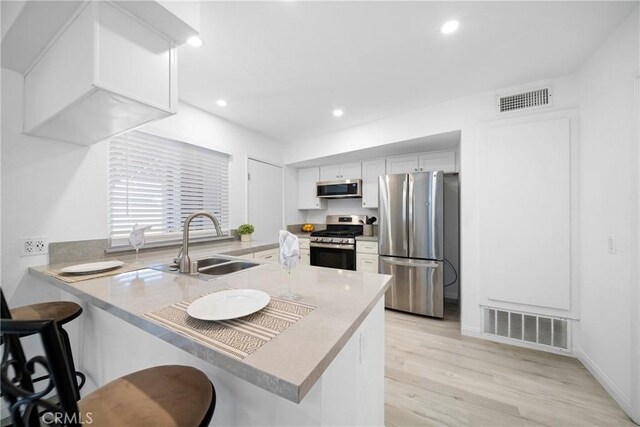 kitchen with a kitchen bar, sink, appliances with stainless steel finishes, and kitchen peninsula