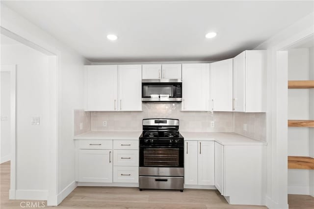 kitchen featuring decorative backsplash, white cabinets, light hardwood / wood-style flooring, and stainless steel appliances