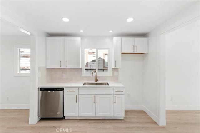 kitchen with tasteful backsplash, dishwasher, sink, and white cabinetry