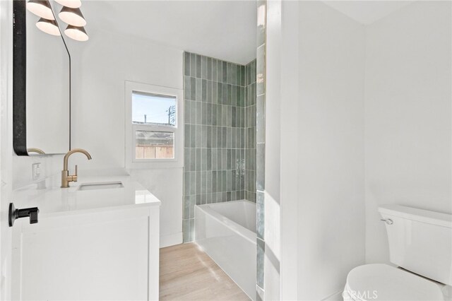 full bathroom with wood-type flooring, toilet, vanity, and tiled shower / bath combo