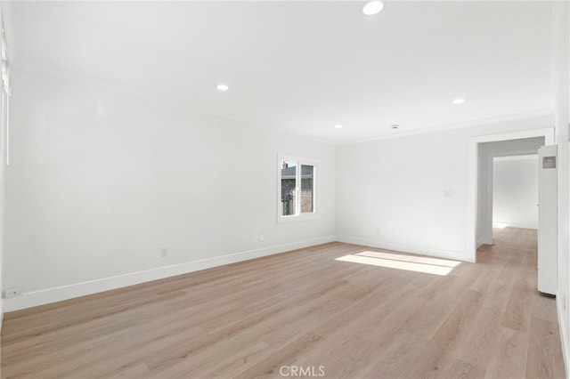 spare room featuring crown molding and light hardwood / wood-style floors