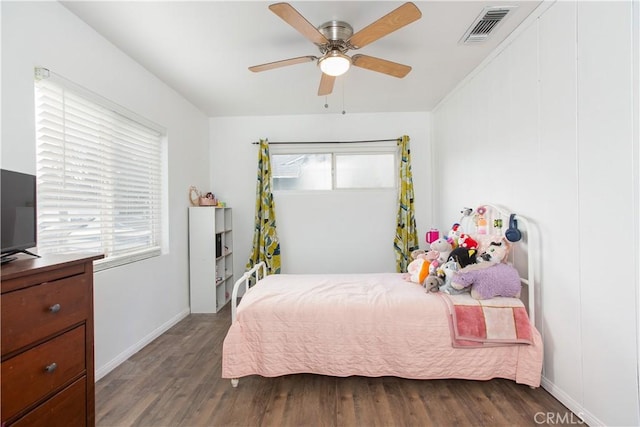 bedroom featuring ceiling fan, multiple windows, and dark hardwood / wood-style floors