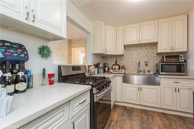 kitchen featuring decorative backsplash, sink, appliances with stainless steel finishes, white cabinets, and dark hardwood / wood-style flooring